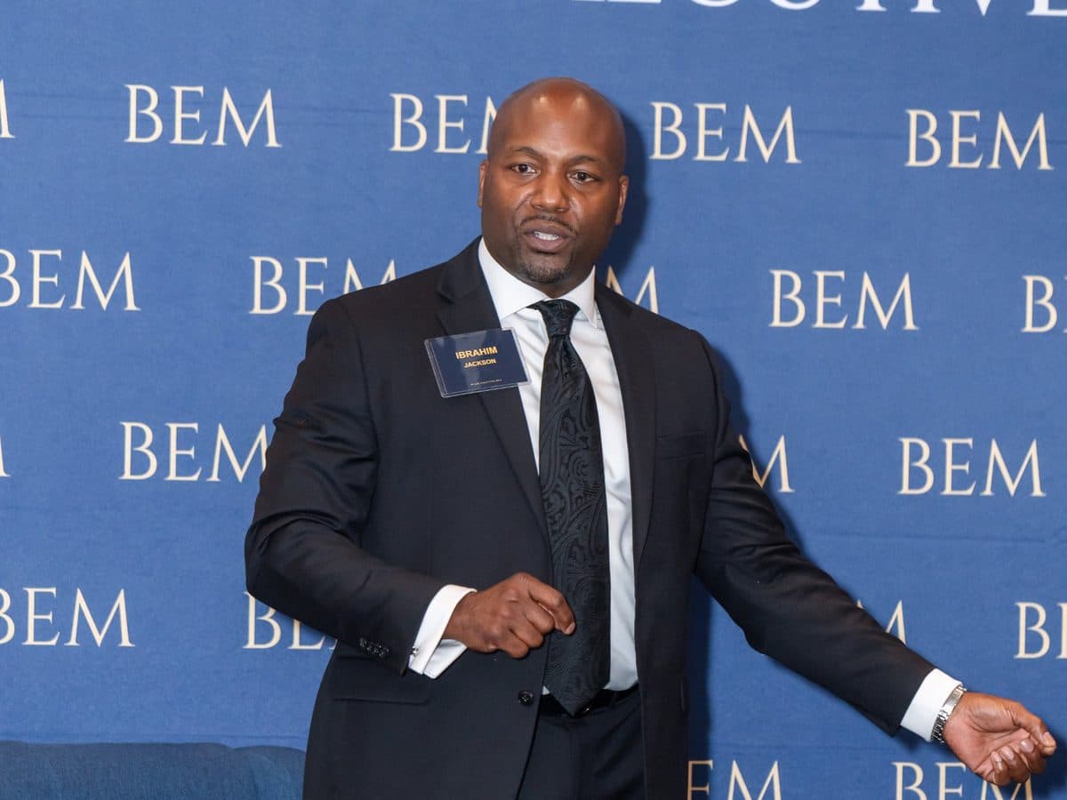 A member speaking in front of the BEM wall at a forum